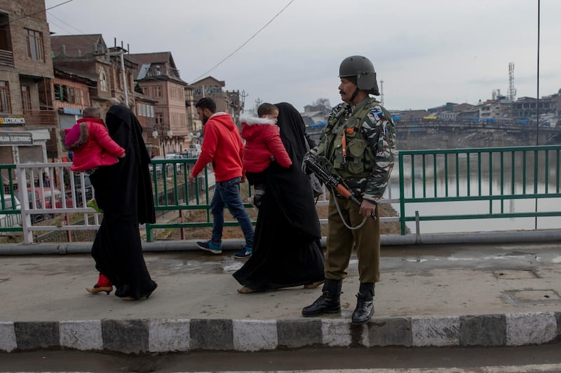 Kashmiri women carry children and walk past an Indian Paramilitary soldier standing guard on a bridge in central Srinagar, Indian controlled Kashmir, Thursday, Feb. 20, 2020. Thursday marks 200 days since India stripped Kashmir of its semi-autonomy and statehood and imposed a total communications blackout. Indian authorities are easing internet access but continue a ban on popular social media platforms such as Facebook, WhatsApp and Twitter. Top Kashmiri leaders also continue to be under arrest. (AP Photo/ Dar Yasin)