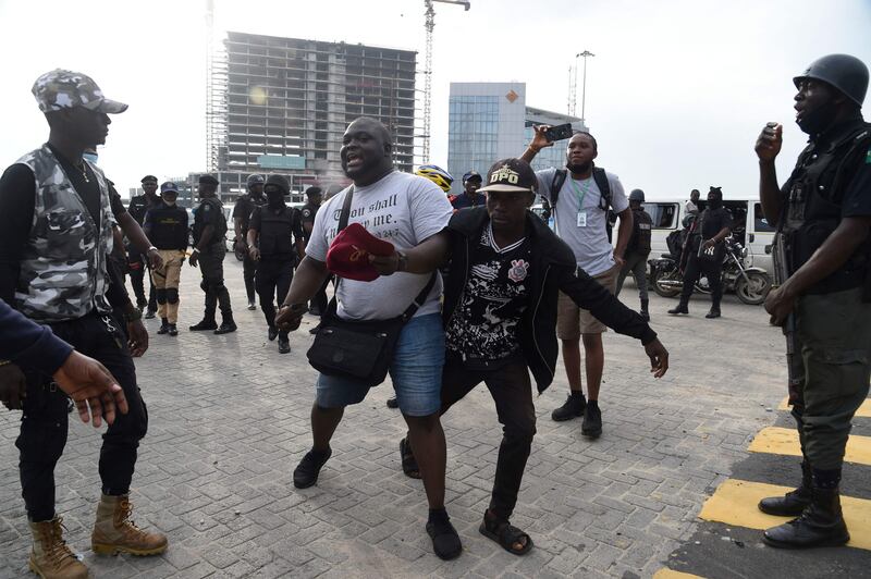 Journalist Abisola Alowode, who was mistaken for a protester, is arrested by police officers during a rally to commemorate the one-year anniversary of EndSARS. AFP
