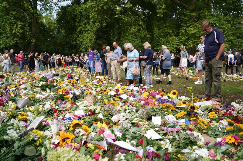 Members of the public view floral tributes in Green Park, near Buckingham Palace. PA