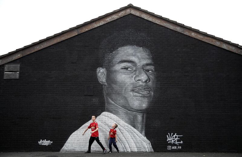 Jacob (left) and Joshua Hallighan in-front of a mural of Manchester United striker Marcus Rashford by Street artist Akse on the wall of the Coffee House Cafe on Copson Street, Withington. PA Photo. Picture date: Sunday November 8, 2020. Manchester United forward Marcus Rashford has drawn widespread praise for his role in highlighting the issue of child food poverty, which has been exacerbated by the economic impact of the coronavirus pandemic. See PA story SOCCER Rashford. Photo credit should read: Martin Rickett/PA Wire. (Photo by Martin Rickett/PA Images via Getty Images)