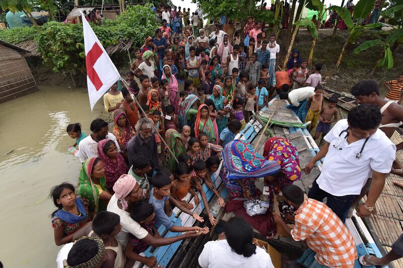 TOPSHOT - Indian medical officials of the Jhargaon Public Health Centre (PHC) distribute medicine to villagers in the flood affected Sagolikota area of Morigaon district, in India's northeastern Assam state, on August 18, 2017.
At least 221 people have died and more than 1.5 million have been displaced by monsoon flooding across India, Nepal and Bangladesh, officials said August 15, as rescuers scoured submerged villages for the missing. / AFP PHOTO / Biju BORO