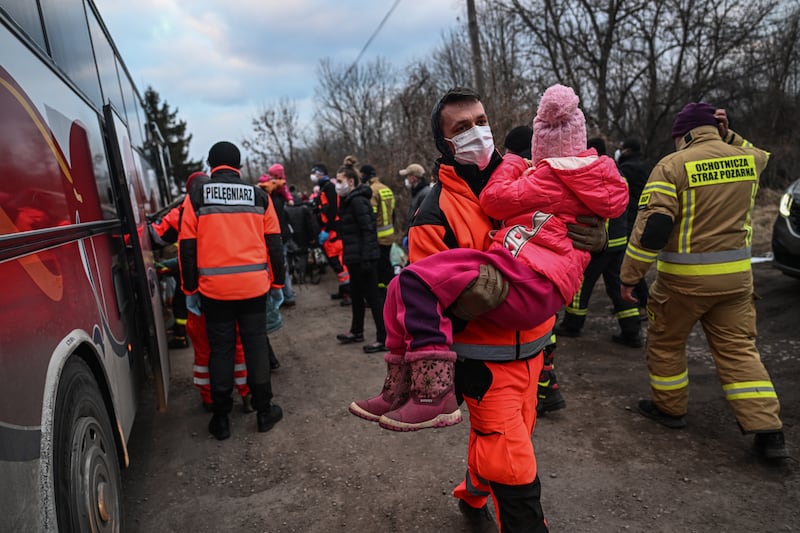 A polish paramedic carries a Ukrainian child to be put in a train carriage renovated for medical transport on March 10 in Medyka, Poland. About 20 children and their families were taken by bus to Medyka. Getty