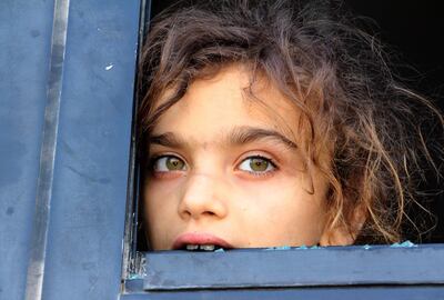 CORRECTION / An evacuated Syrian girl from the area of Fuaa and Kafraya in the Idlib province, looks out of a broken bus window as it passes the al-Eis crossing south of Aleppo during the evacuation of several thousand residents from the two pro-regime towns in northern Syria on July 19, 2018.  As the buses passed through rebel-held territory, people threw rocks at them, which shattered the windows during the evacuation which put an end to one of the longest sieges of the country's seven-year civil war. Fuaa and Kafraya were the last remaining areas under blockade in Syria and a rare example of pro-government towns surrounded by rebel forces. / AFP / Ibrahim YASOUF
