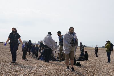 Immigration enforcement officers and members of the RNLI assist a group of migrants after they were brought to Dungeness beach in Kent on Monday. Photo: PA 