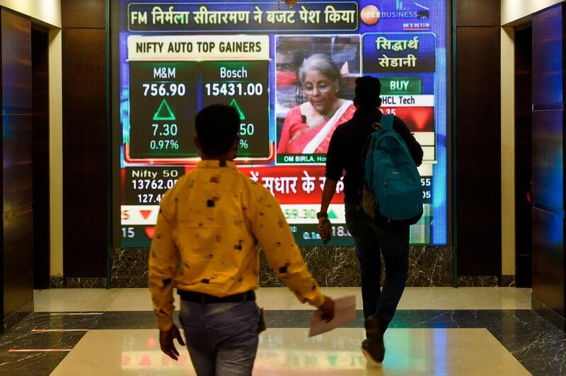 Office workers walk past a digital screen showing Indian Finance Minister Nirmala Sitharaman delivering the budget speech in parliament, at the Bombay Stock Exchange (BSE) in Mumbai on February 1, 2021. / AFP / Punit PARANJPE
