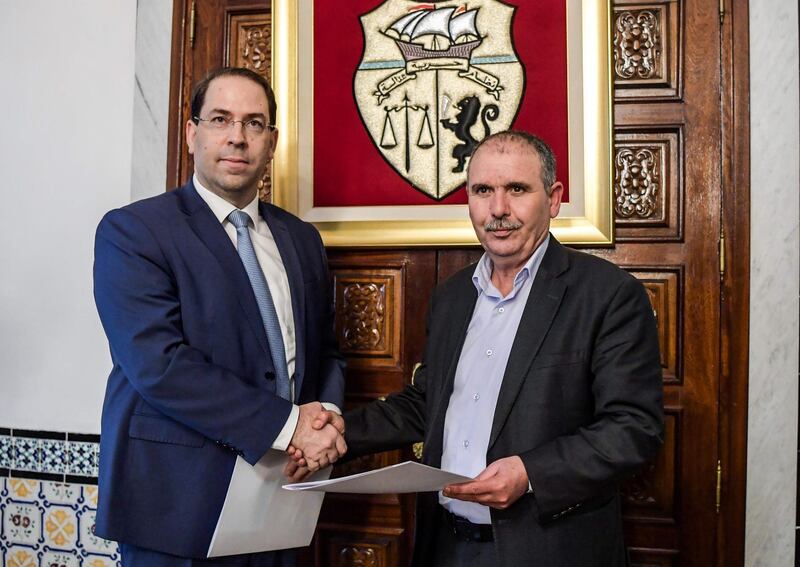 Tunisian Prime Minister Youssef Chahed (L) shakes hands with the Secretary-General of the Tunisian General Labour Union (UGTT) Noureddine Taboubi, after the signing of an agreement over wage hike demands, in the capital Tunis on February 7, 2019. The agreement averts a further round of paralysing strikes. The UGTT brought the North African country to a standstill in January with a 24-hour strike by public sector workers to secure wage hikes and economic reforms. / AFP / FETHI BELAID
