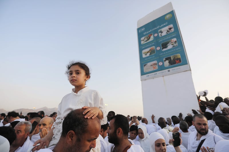 A Muslim man carries a child on his shoulders as pilgrims pray on Mount Arafat. EPA