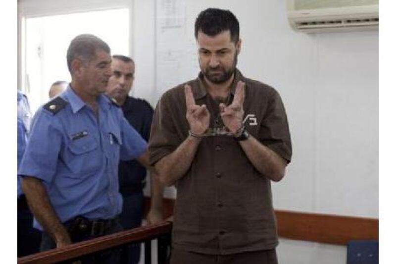 Abdullah Abu Rahme, 39, makes V-signs inside the courtroom at Ofer military jail near Ramallah yesterday during his sentencing. Mr Rahme's group of protesters opposed Israel's separation barrier.