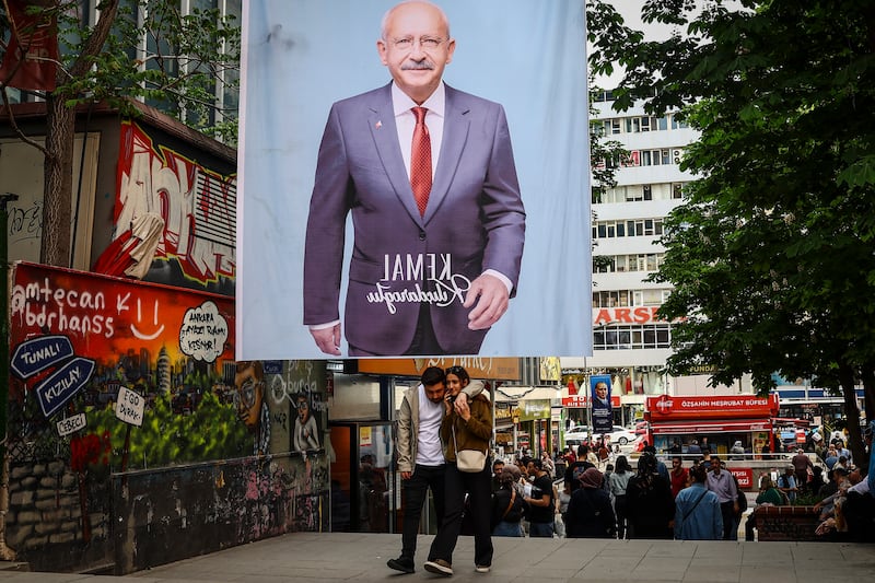 A couple walk under a poster of Turkish presidential candidate Kemal Kilicdaroglu, leader of the opposition Republican People's Party, the day after the general election, in Ankara. EPA