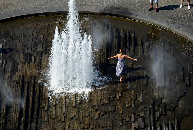 A woman cools off in a fountain at the Lustgarten in central Berlin. AFP