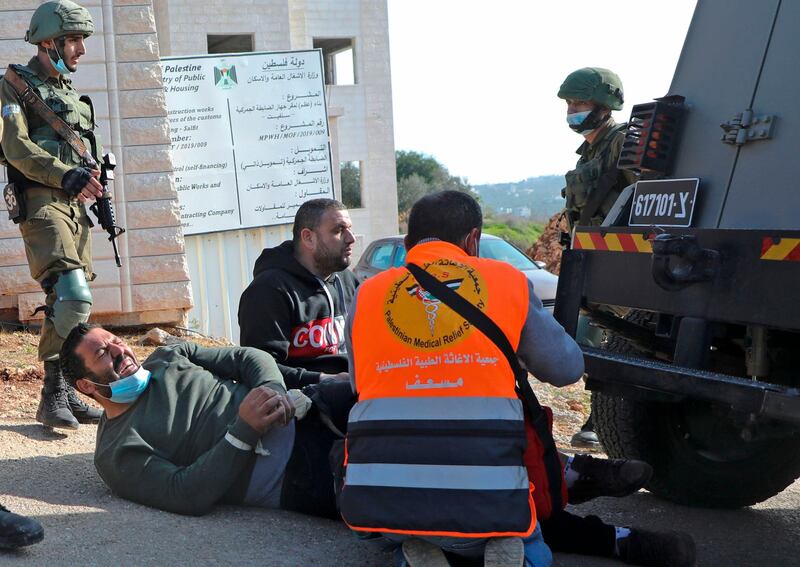 Israeli soldiers arrive to arrest an injured Palestinian protester who was hit by an Israeli security vehicle while fleeing amid clashes following a demonstration against the expansion of settlements on December 4, 2020.  AFP
