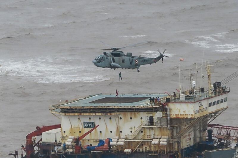 This handout photograph taken on May 18, 2021 and released by the Indian Navy shows stranded workers from a barge, which had gone adrift amidst heavy rain and strong winds due to Cyclone Tauktae, being airlifted by naval personnel on an Indian Navy Seaking helicopterduring an evacuation operation, in the Arabian sea. At least 27 people were dead and more than 90 missing on May 18 after a monster cyclone slammed India, compounding the country's woes as it recorded a new record number of coronavirus deaths in 24 hours. / AFP / INDIAN NAVY / -
