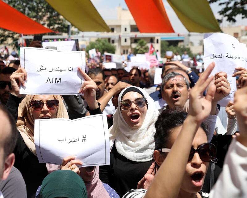 epa06773310 Jordanians hold placards reading in Arabic 'I am an engineer not an ATM' and 'General strike' and shout slogans against the newly proposed income tax reforms while some of the strikers are gathered outside the Jordanian professional associations building, during the first general strike to take place in Jordan, Amman, Jordan, 30 May 2018. Various Jordanian professional associations called on 30 May for a general strike to protest against the newly announced income taxes law. The law has been prepared and sent to the parliament, the strikers demand its withdrawal and advise for another strike a week later if its demand are not met.  EPA/ANDRE PAIN