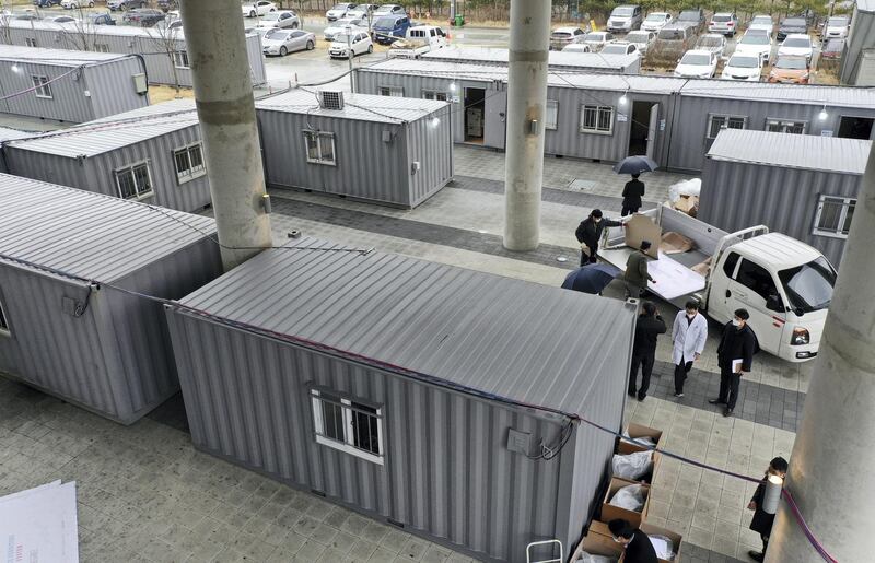 Workers move equipments into containers set up as a makeshift medical facility to accommodate COVID-19 patients at a hospital's grounds in Daegu, South Korea, Friday, Feb. 28, 2020. Japan's schools prepared to close for almost a month and entertainers, topped by K-pop superstars BTS, canceled events as a virus epidemic extended its spread through Asia into Europe and on Friday, into sub-Saharan Africa. (Kim Hyun-tae/Yonhap via AP)