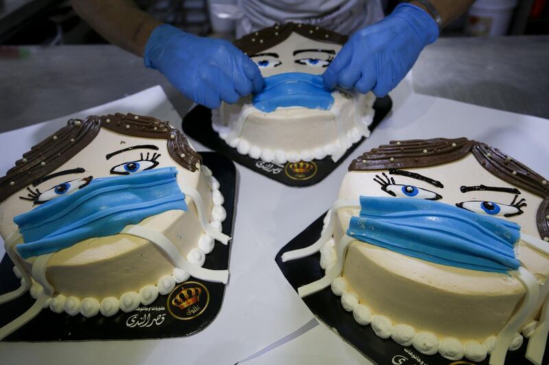 A Palestinian baker finishes a cake, that portrays a woman wearing a facemask, at his shop in Khan Yunis in the southern Gaza Strip. AFP