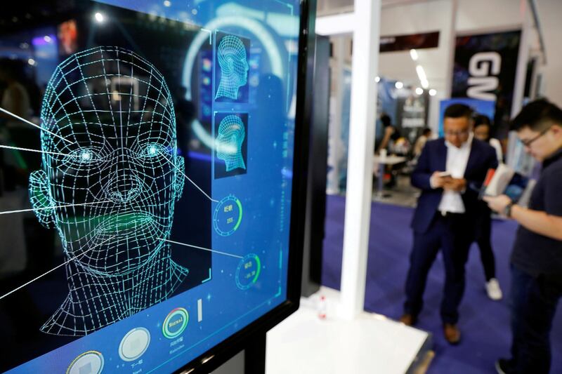 FILE PHOTO: Visitors check their phones behind the screens advertising facial recognition software during Global Mobile Internet Conference at the National Convention in Beijing, China April 27, 2018. REUTERS/Damir Sagolj/File Photo