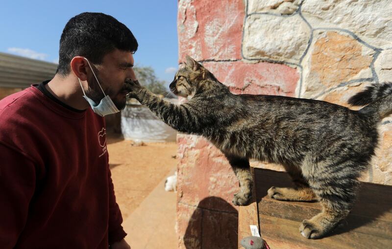 Behind the mask: a worker and a cat interact at Ernesto's Sanctuary in Idlib, Syria. Reuters