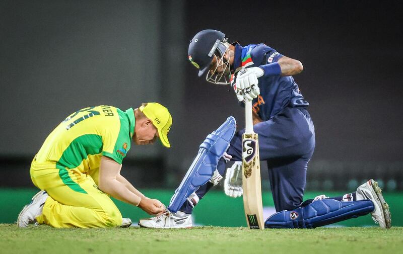 Australia’s David Warner ties the shoelace for India’s Hardik Pandya. AFP