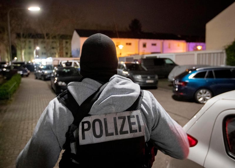 A police officer guards the road in front of a house that is searched through by police in Hanau, Germany. AP