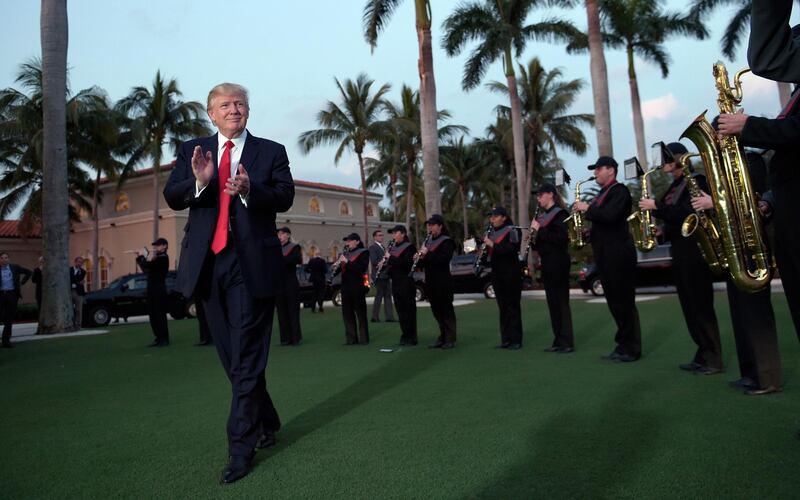 FILE- In this Feb. 5, 2017, file photo, President Donald Trump listens to the Palm Beach Central High School Band as they play at his arrival at Trump International Golf Club in West Palm Beach, Fla. (AP Photo/Susan Walsh, File)