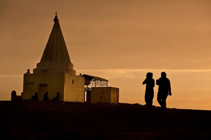 FILE - In this May 18, 2016 file photo, the sun sets as women visit a Yazidi shrine overlooking at Kankhe Camp for the internally displaced in Dahuk, northern Iraq. The enslavement of Iraqi Yazidi women by the Islamic State group has left a heartbreaking legacy -- hundreds of children fathered by militants. While some of the women want nothing to do with babies born of rape and slave, some want to keep them, but they face rejection by families traumatized by the militants who killed hundreds of Yazidis and tried to wipe out the community. (AP Photo/Maya Alleruzzo, File)