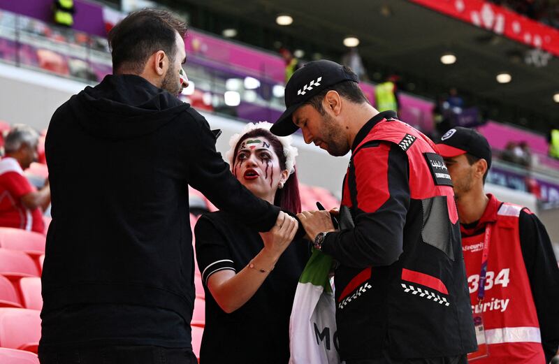 Police officers confiscate an Iran fan's 'Women Life Freedom' flag inside the stadium before the match. Reuters