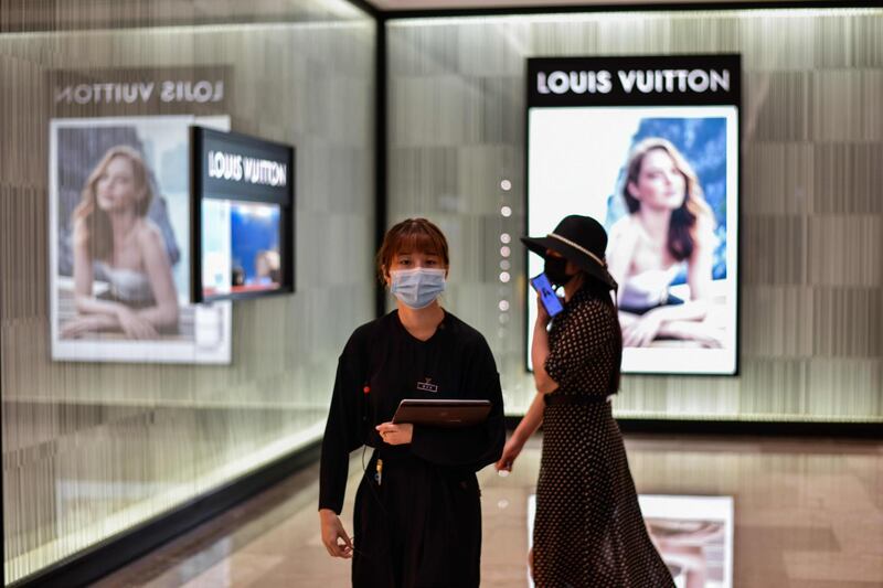 People wearing face masks walk past a boutique shop in Wuhan, in China's central Hubei province. AFP