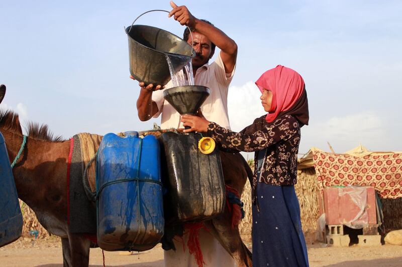 A man helps a girl to fill jerry cans with water from a cistern at a make-shift camp for displaced Yemenis, in the northern Hajjah province on April 29, 2020, amid a severe shortage of water. Essa Ahmed/ AFP