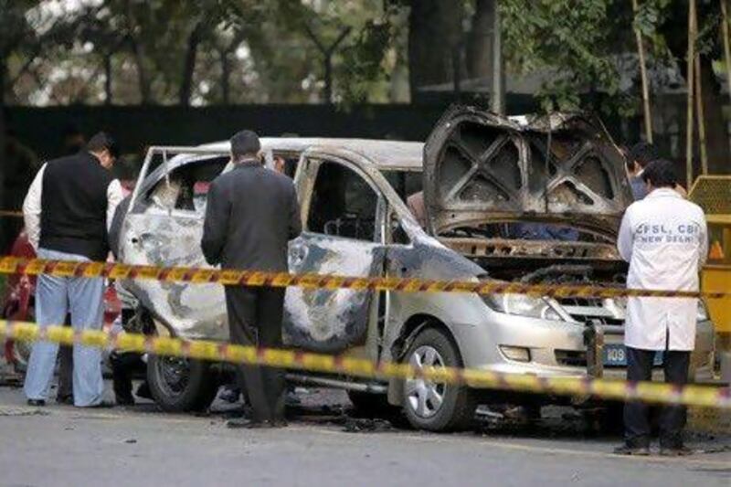 Indian security and forensic officials examine a car belonging to the Israel embassy after an explosion in New Delhi.