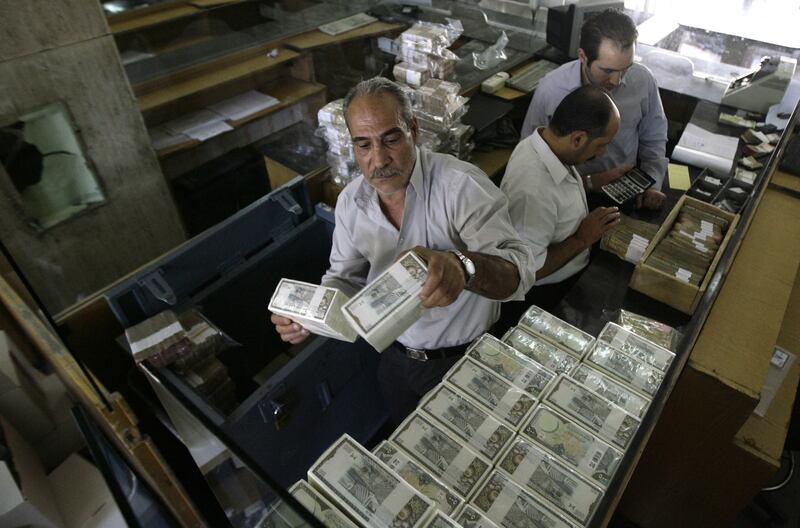 A banker stacks packed Syrian lira bills at the Central Bank in Damascus on August 25, 2011. US sanctions have forced Syria to stop all transactions in US dollars, with the country turning completely to euro deals, the governor of the Central Bank Adib Mayaleh told the AFP during an interview. 