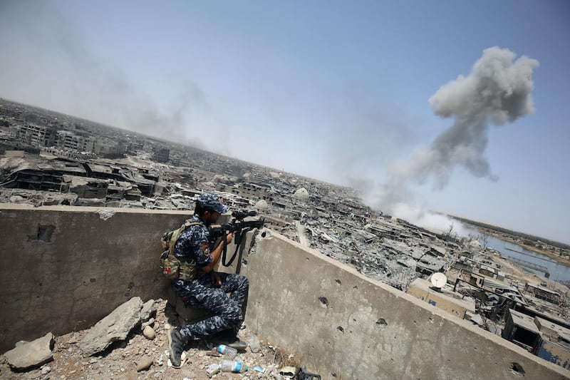 (FILES) In this file photo taken on July 09, 2017 An Iraqi forces sniper looks on as smoke billows, following an airstrike by US-led international coalition forces targeting Islamic State (IS) group, in the Old City of Mosul on July 9, 2017, as their part of the battle has been declared accomplished, while other forces continue to fight Islamic State (IS) jihadists in the city. Iraqi forces announced the "liberation" of the country's second city on July 10, 2017, after a bloody nine-month offensive to end the Islamic State (IS) group's three-year rule there. 
Scores of people are still displaced in and around Mosul as the city lies in ruins, one year after it was retaken from IS. 

 / AFP / Ahmad al-Rubaye
