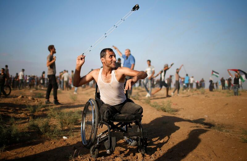 A disable Palestinian uses a sling to hurl stones at Israeli troops during a protest demanding the right to return to their homeland at the Israel-Gaza border, in Gaza. Reuters