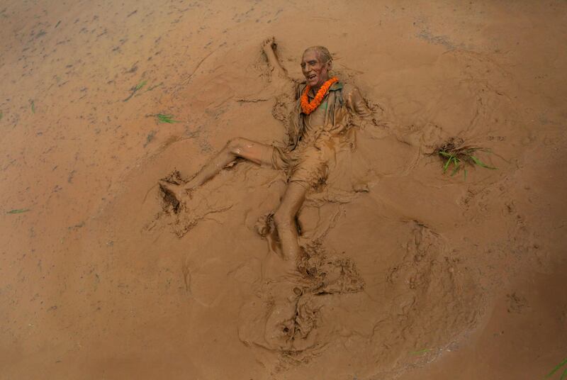 An elderly Nepalese man falls in the mud in a paddy field while playing with another during 'Asar Pandra', or paddy plantation day in Dhading district, Nepal. AP
