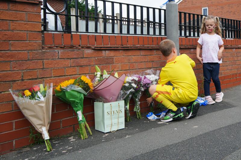 Children leave flowers near the scene in Kingsheath Avenue, Knotty Ash, Liverpool. PA