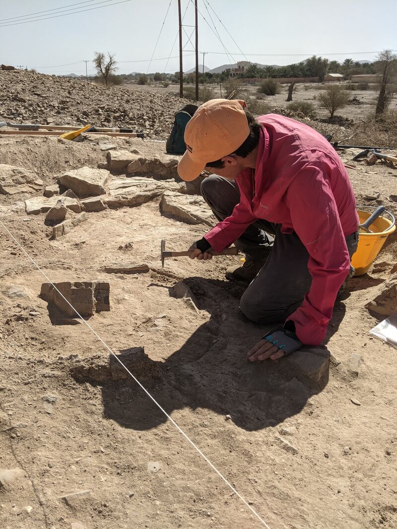 A team member carefully digs out a tanoor, or hearth, at the site.