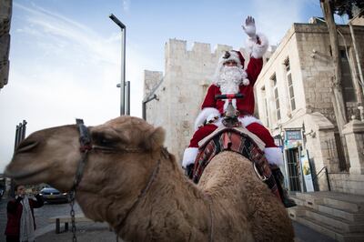 epa06401137 A Palestinian dressed in a Santa Claus costume riding a camel next to the walls of the Old City of Jerusalem, 21 December 2017. In Jerusalem and in the neighbouring city of Bethlehem a variety of events such as Christmas Markets, concerts and carols in many churches and places are planned over the Christmas holidays with organizers expecting thousands of pilgrims to celebrate at the historic Christian sites.  EPA/ABIR SULTAN