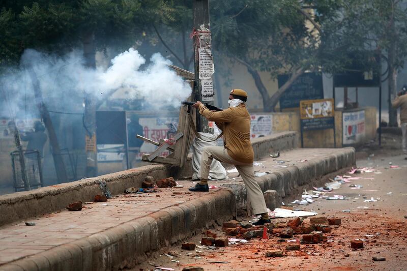 A policeman fires a teargas shell during a protest against a new citizenship law at the Seelampur area of New Delhi, India. AP