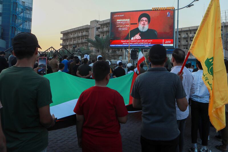 Iraqi demonstrators watch a speech from Lebanon's militant Hezbollah leader Sayyed Hassan Nasrallah on a screen as they hold flags of, Palestinians and Hezbollah during a pro-Palestinian rally in Basra, Iraq, Friday, Nov.  3, 2023.  (AP Photo / Nabil al-Jurani)