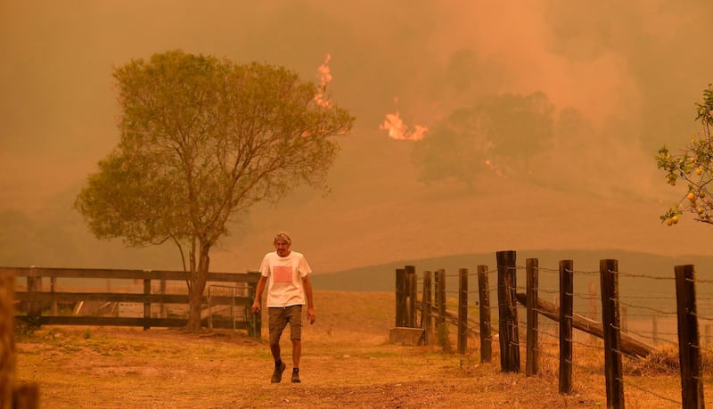 A man walks on a farm as flames approach near the town of Taree, 350kms north of Sydney. AFP