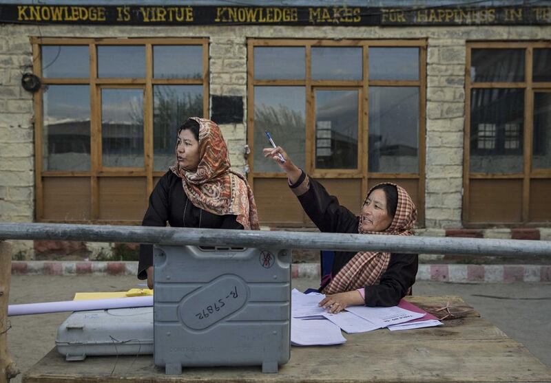 Election workers check voting machines as they prepare to distribute them to workers at a central collection point before heading to polling stations.