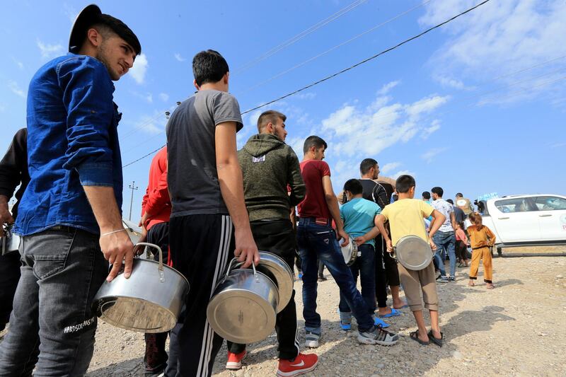 Syrian displaced families, who fled violence after the Turkish offensive in Syria, stand in queue to get their food from Barzani charity at a refugee camp in Bardarash on the outskirts of Dohuk, Iraq. Reuters