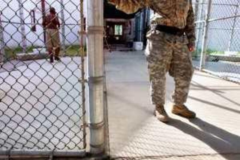 In this photo reviewed by the U.S. Military, a guard leans on a fencepost as a Guantanamo detainee, left, jogs inside the exercise yard at Camp 5 detention center on the U.S. Naval Base in Guantanamo Bay, Cuba, Wednesday, Jan. 21, 2009. The Obama administration will close the Guantanamo Bay detention center within a year and halt U.S. military trials of terror suspects held there under a draft order obtained Wednesday.  (AP Photo/Brennan Linsley, Pool) *** Local Caption ***  XBL101_US_Obama_Guantanamo.jpg