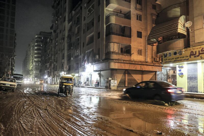 A tuktuk (motorised rickshaw) and a car drive through heavy mud along a street in the Faisal district of the Egyptian capital's twin city of Giza late on October 22, 2019. - Rare heavy rains disrupted traffic across the Egyptian capital Cairo and caused delays in flights late night on October 22, airport officials said. Prime Minister Mostafa Madbouli also announced the closure of universities and schools in some areas of Cairo, Giza and Qalyubia following bad weather forecasts from the country's Meteorological Authority. (Photo by Mohamed el-Shahed / AFP)