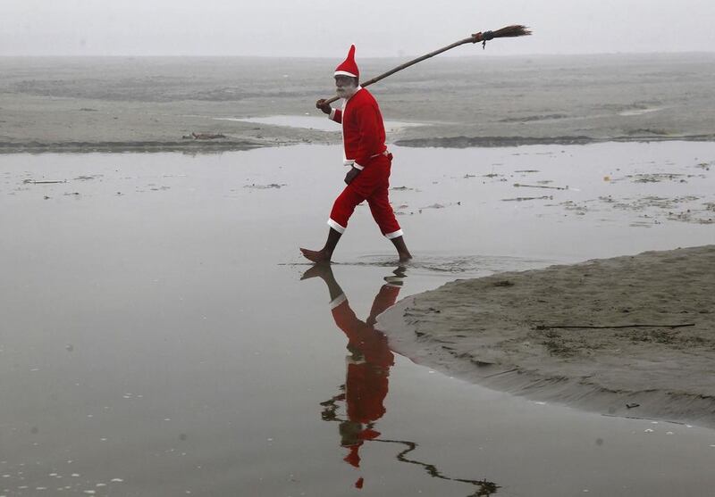 A Hindu devotee wearing a Santa Claus costume walks after cleaning banks of the river Ganges in Allahabad, India.  Jitendra Prakash / Reuters