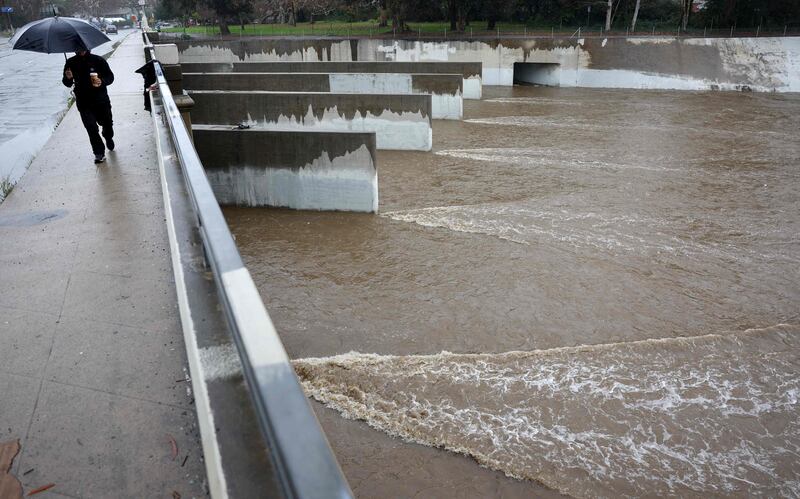 A man walks crosses the Los Angeles River in Los Angles as Californian storms continue. Getty / AFP