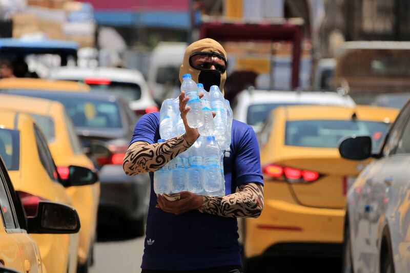 An Iraqi street seller offers motorists cold water in central Baghdad. EPA