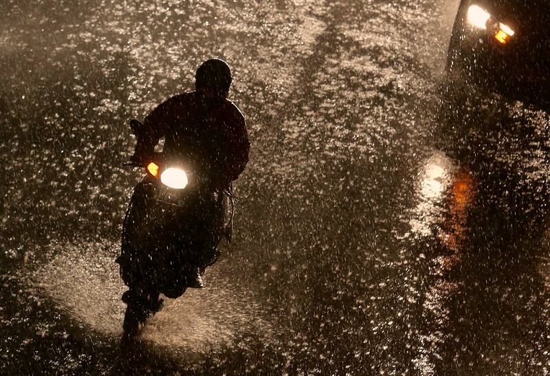 A motorist rides during a heavy rain in Bangalore on August 11.  Jagadeesh NV / EPA