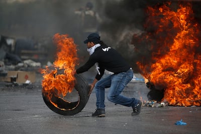 A Palestinian pushes a burning tyre during clashes with Israeli troops at the northern entrance of the West Bank city of Ramallah. EPA
