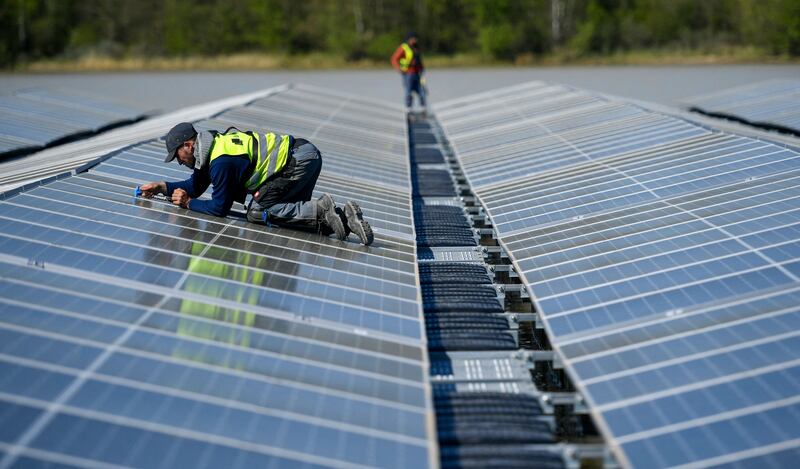 A worker fixes solar panels at a floating photovoltaic plant in Haltern, western Germany. The UAE and Germany are collaborating to create clean energy strategies. AFP