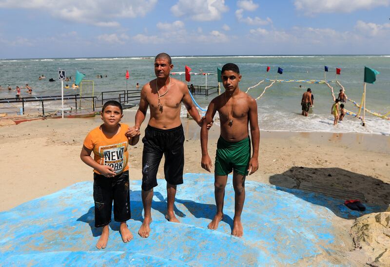 A lifeguard helps visually impaired children make their way along Al Mandara beach. Reuters